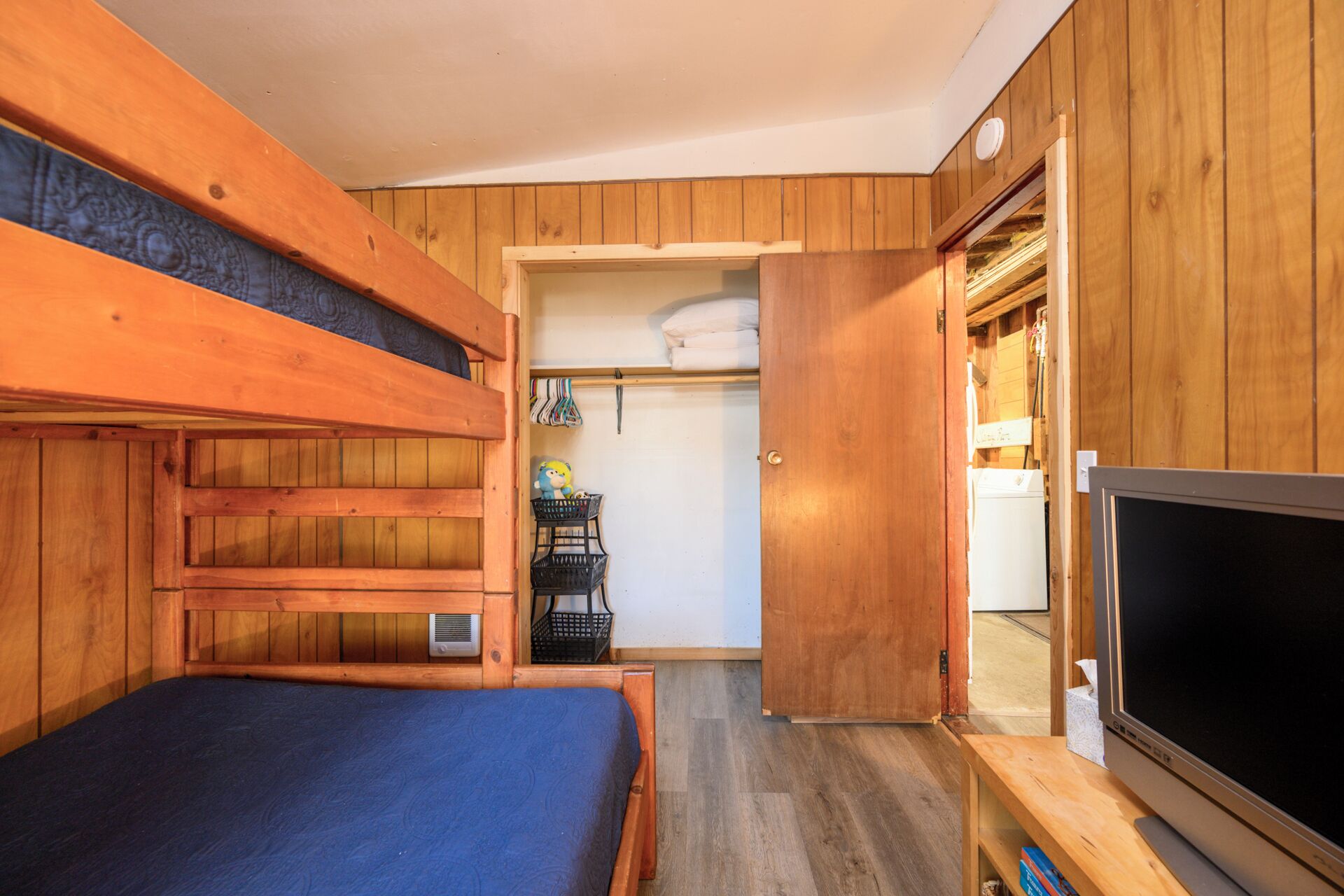 A wooden room with bunk beds, a television, and a wardrobe.