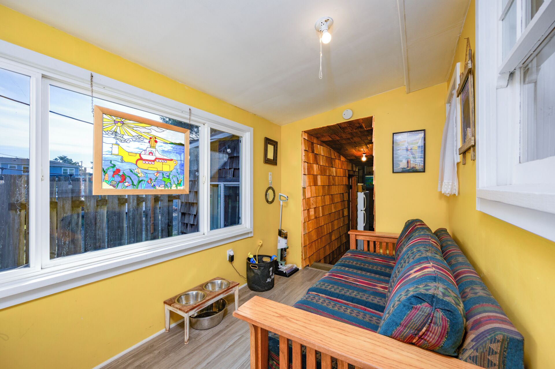 Una habitación acogedora con un banco de madera, un sofá colorido y una pared de madera.