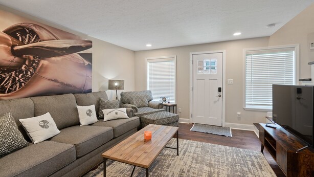 A living room with a sectional sofa, a coffee table, a television, and a large wall mural.