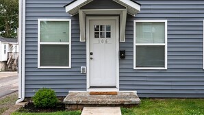 A house with a white front door, number 106, and two windows on either side.