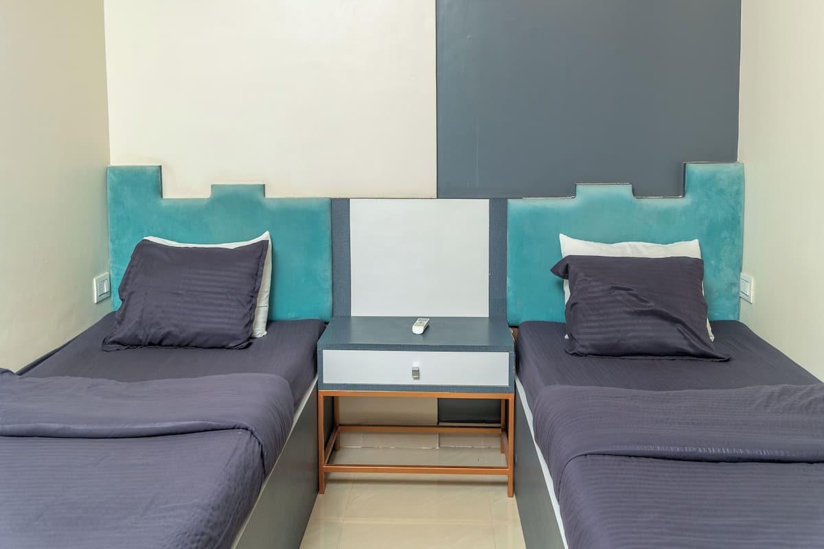 A room with two beds, a small desk, and a wall-mounted control panel.