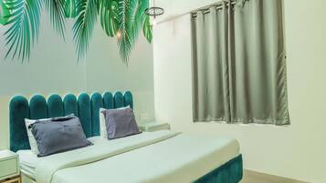 A modern bedroom with a teal upholstered headboard, a white bedspread, and two pillows.