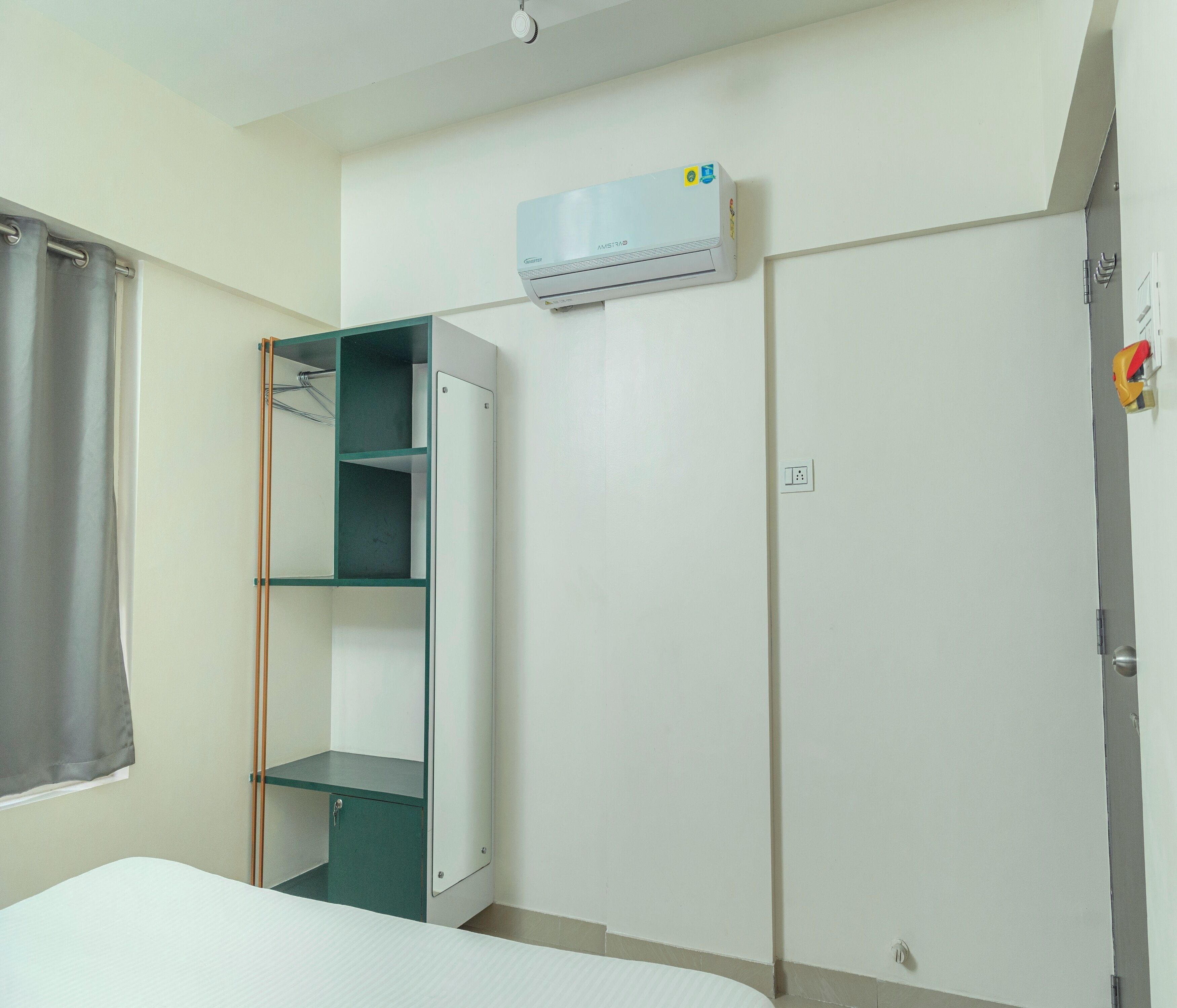 Una habitación con cama, armario, estantería y aire acondicionado.