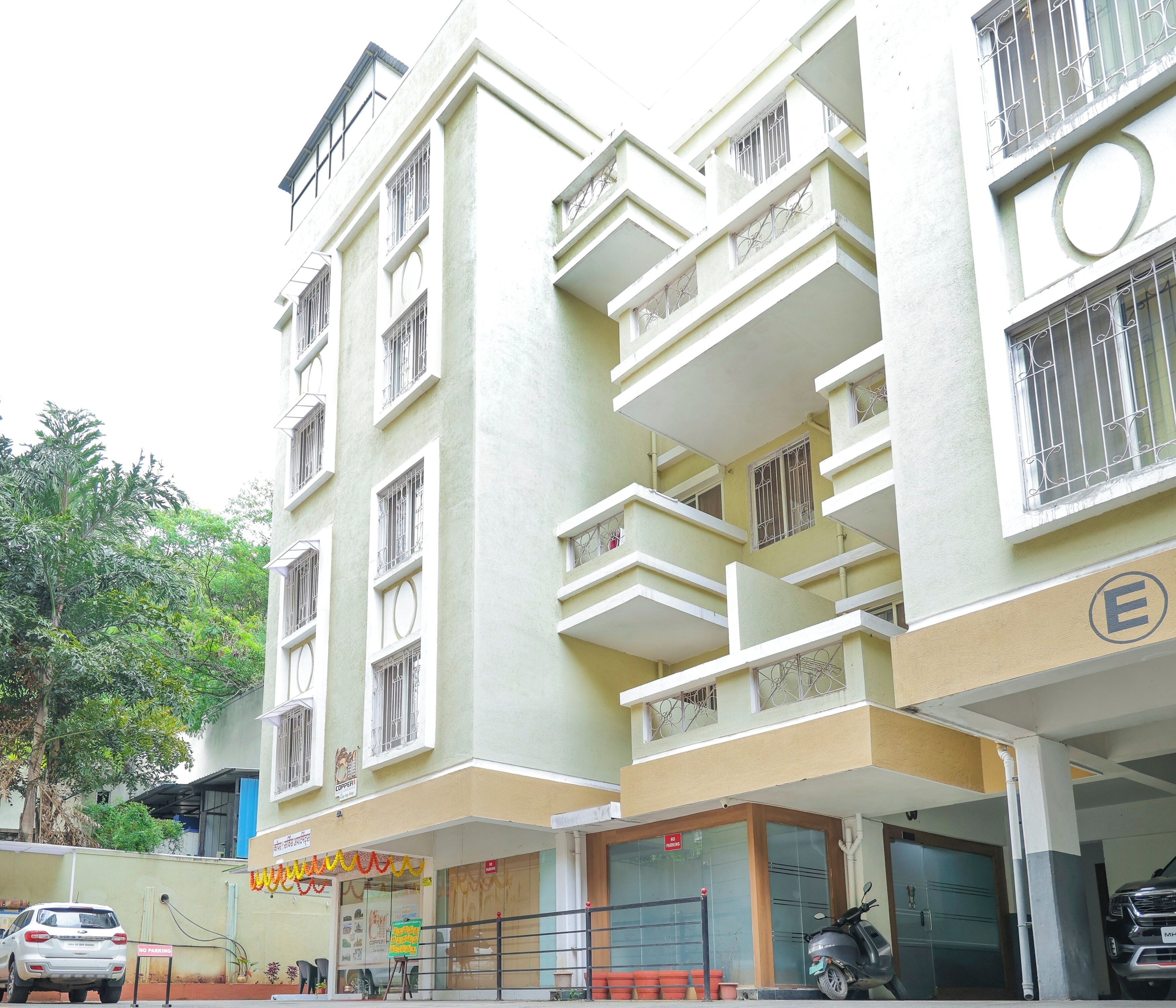 A multi-story building with balconies, a "No Parking" sign, and a parked scooter.