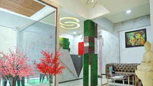 A modern lobby with a reception desk, a green wall, a Buddha statue, a sofa, and a coffee table. - Copper 11 Service Apartments -SB Road, Shivaji Nagar, Pune (Pune)