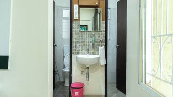 A bathroom with a toilet, sink, and a pink trash bin.