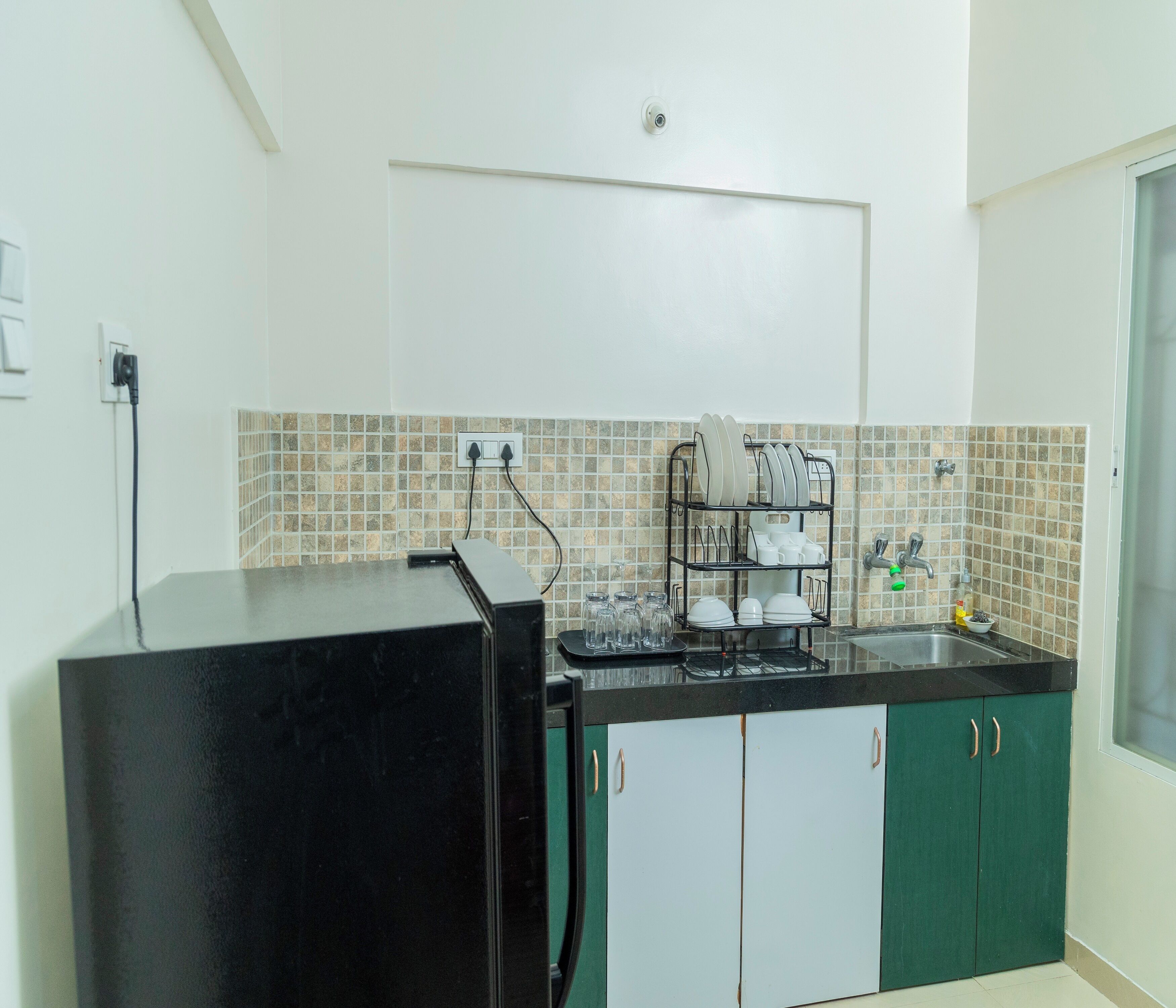 A kitchen with a black refrigerator, a sink, and a dish rack.