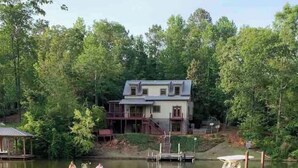 A lakeside view with boats docked, a house in the background, and a grassy area in the foreground. - Creekside Cottage-kayaks/fire pit/pet friendly (Jacksons' Gap)