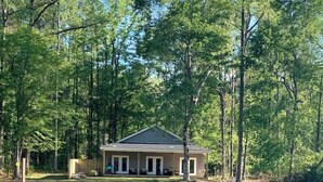 A cabin with a dock extending into a lake, surrounded by dense trees. - Creekside Cottage-kayaks/fire pit/pet friendly (Jacksons' Gap)