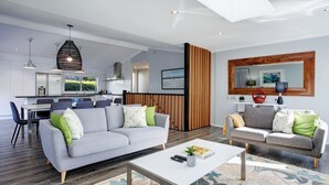 Un salon moderne avec deux canapés, une table basse et un coin repas avec des chaises.