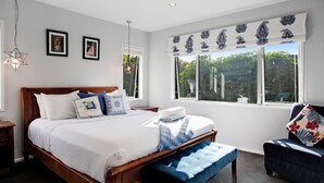 Une chambre à coucher avec un grand lit, une table de chevet, un banc, une chaise et une fenêtre donnant sur un paysage verdoyant.