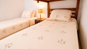 Ett hotellrum med två separata sängar, var och en med ett blommigt sängöverkast, ett nattduksbord med en lampa och en sänggavel i trä.