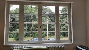 A room with a large window overlooking a garden and a parked car.