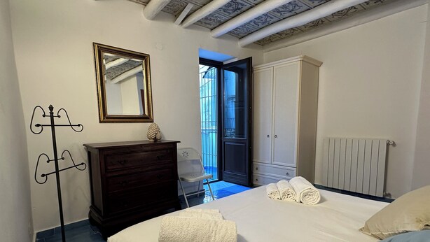 Un dormitorio con cama, cómoda, espejo y radiador.