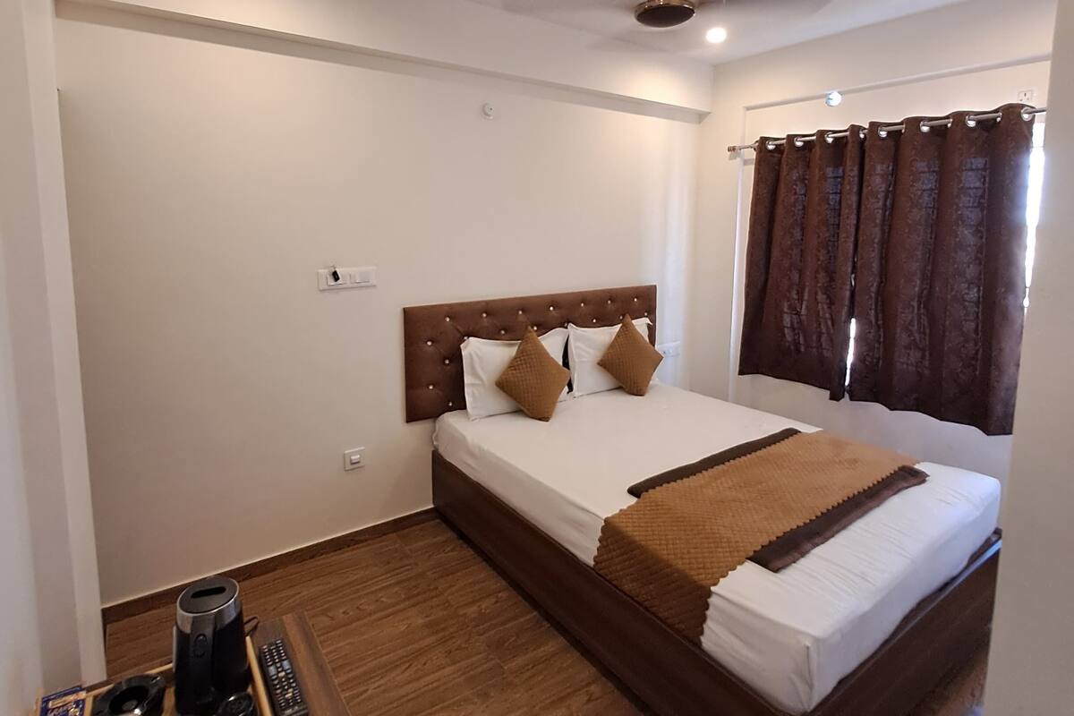 Un dormitorio ordenado con cama, mesita de noche con un neceser y ventilador de techo.