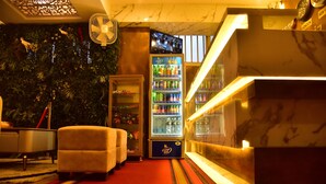 A hotel lobby with a seating area, a minibar, and a large beverage refrigerator. - Meadows Inn (Mysore)