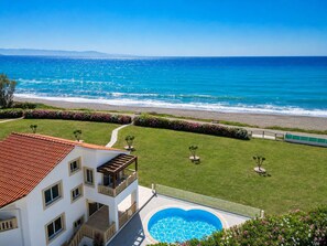 Un bâtiment à deux étages doté d’une piscine, d’un chemin menant à la plage et offrant une vue sur l’océan.
