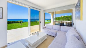 Een moderne woonkamer met een grote schuifglazen deur die leidt naar een balkon met uitzicht op zee.