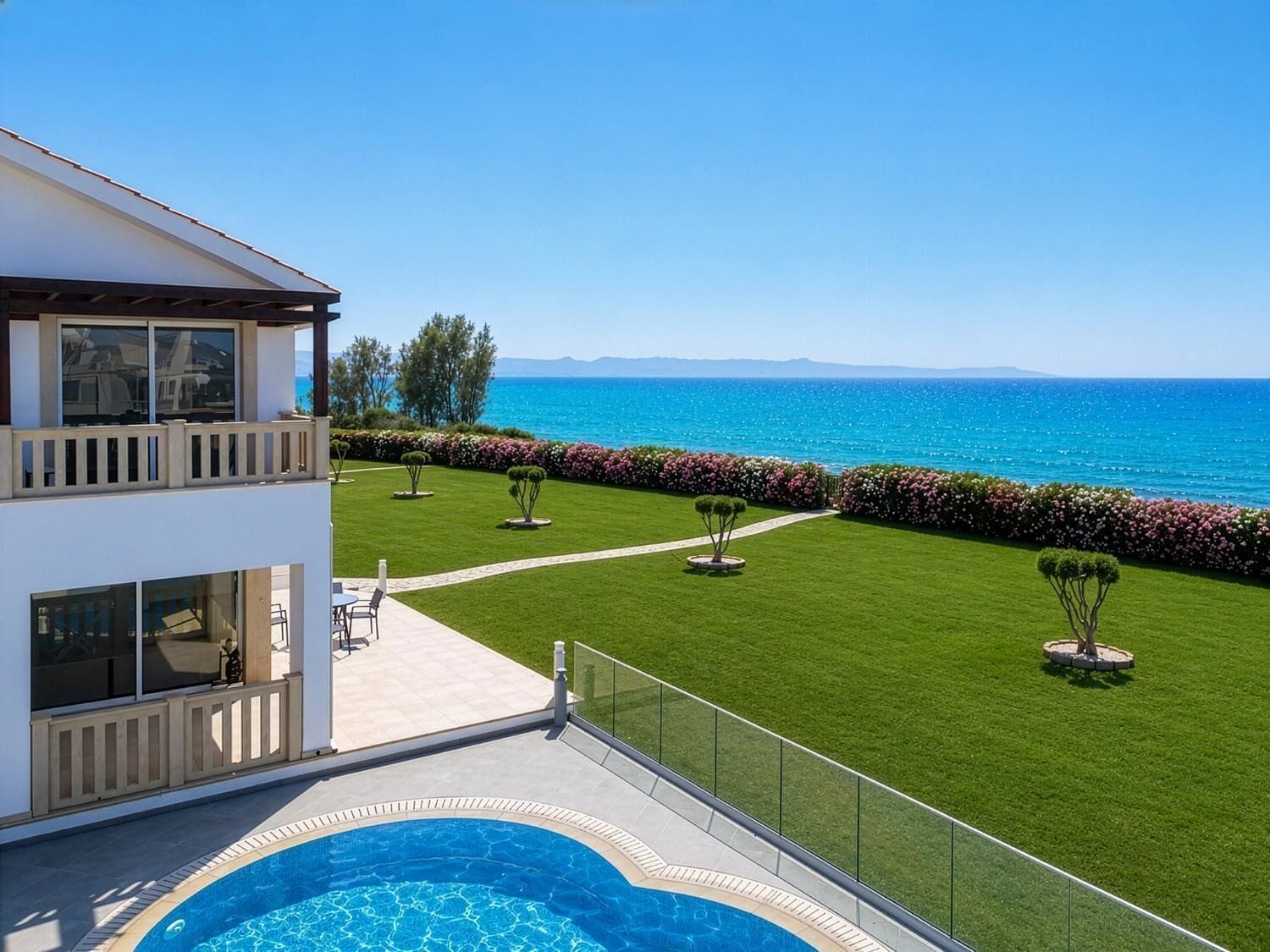 Une maison moderne à deux étages, dotée d’une piscine, d’une pelouse bien entretenue et offrant une vue sur la mer.