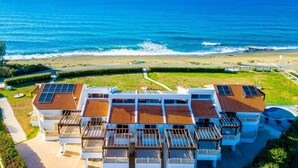 Un hotel costero con varios balcones, vista a la playa y paneles solares en el techo.