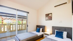 Un dormitorio con dos camas, un ventanal corredero a un balcón y un cuadro en la pared.