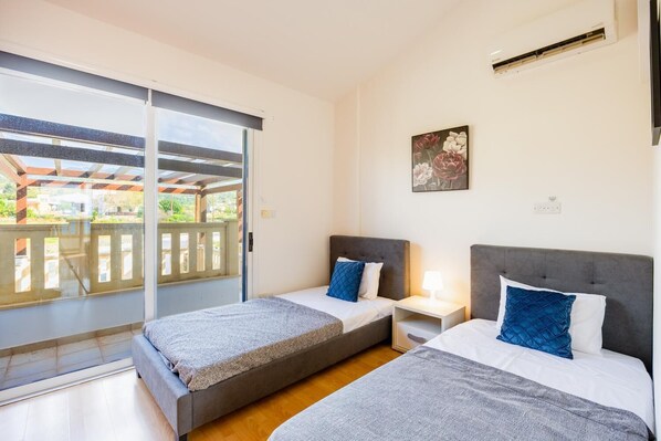 Une chambre avec deux lits, une porte-fenêtre coulissante donnant sur un balcon et un tableau au mur.