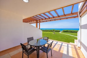 A covered patio with a table and chairs, a view of the sea, and a well-maintained lawn. - Villa Hera - Two Bedroom Villa, Sleeps 4 (Agia Marina Chrysochous)
