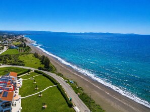 A coastal property with a curved road, a beach, and a view of the ocean.