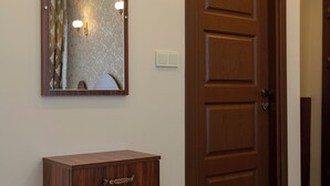 A wooden door with a mirror above it, a small wooden desk, and a light fixture on the wall. - Capricorn by Otantik Suites (Istanbul)