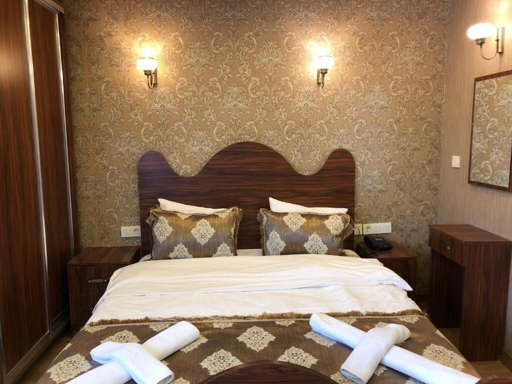 Una habitación de hotel con una cama grande, dos lámparas adosadas a la pared y un espejo en la pared.