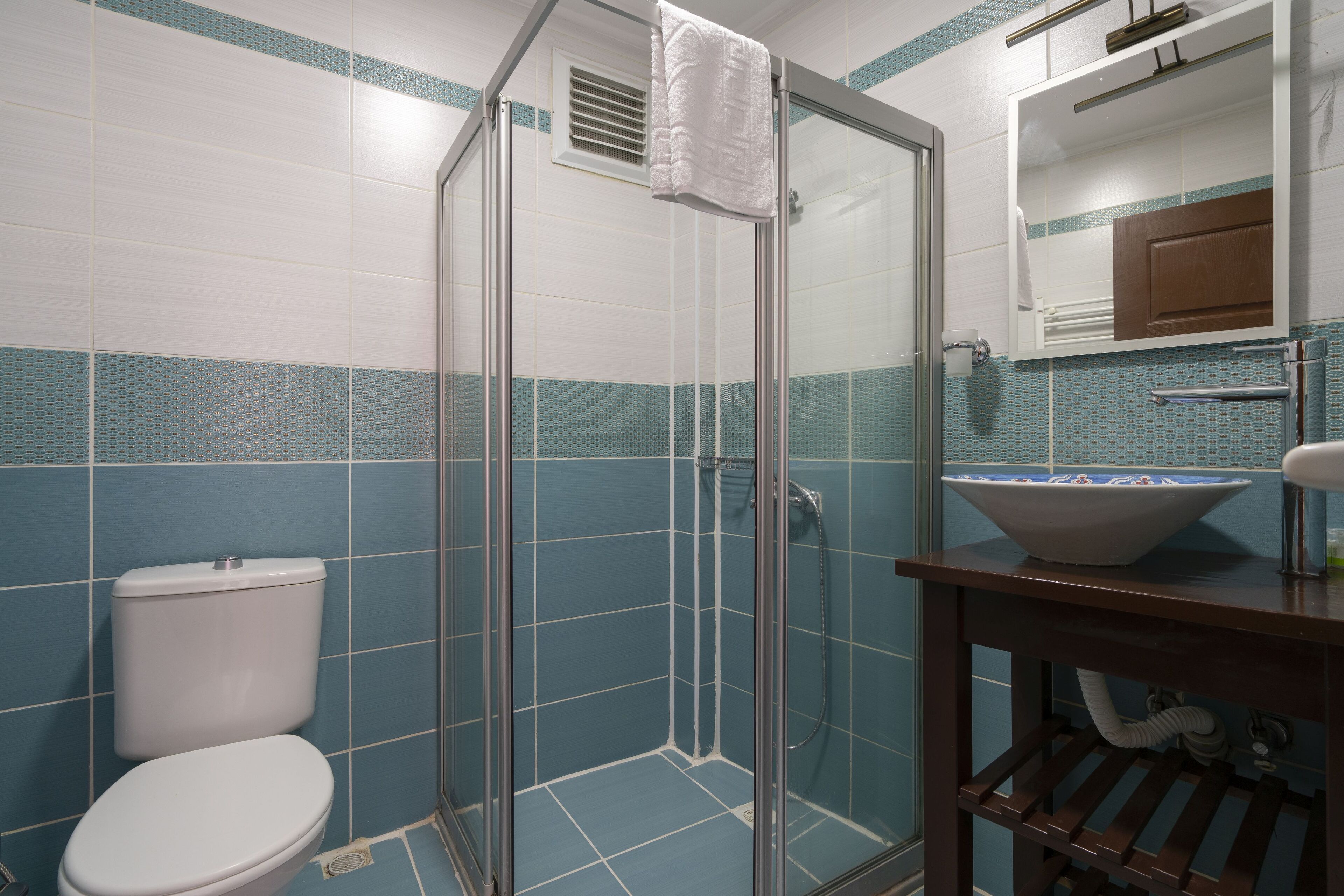Un baño con cabina de ducha de vidrio, inodoro y lavabo.