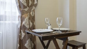 A dining area with a table set for two, a wooden stool, and a painting on the wall. - Capricorn by Otantik Suites (Istanbul)