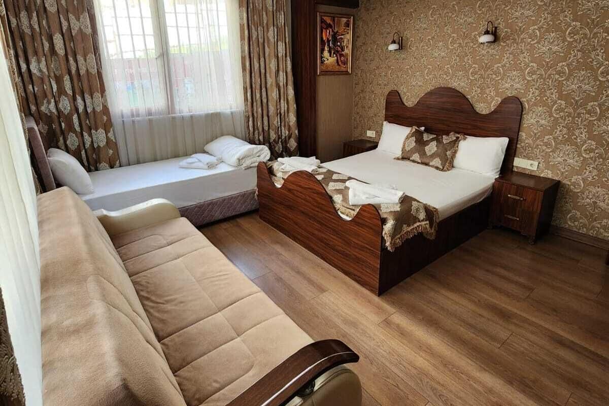 A hotel room with a large bed, a sofa, a small table, and a wall-mounted lamp.