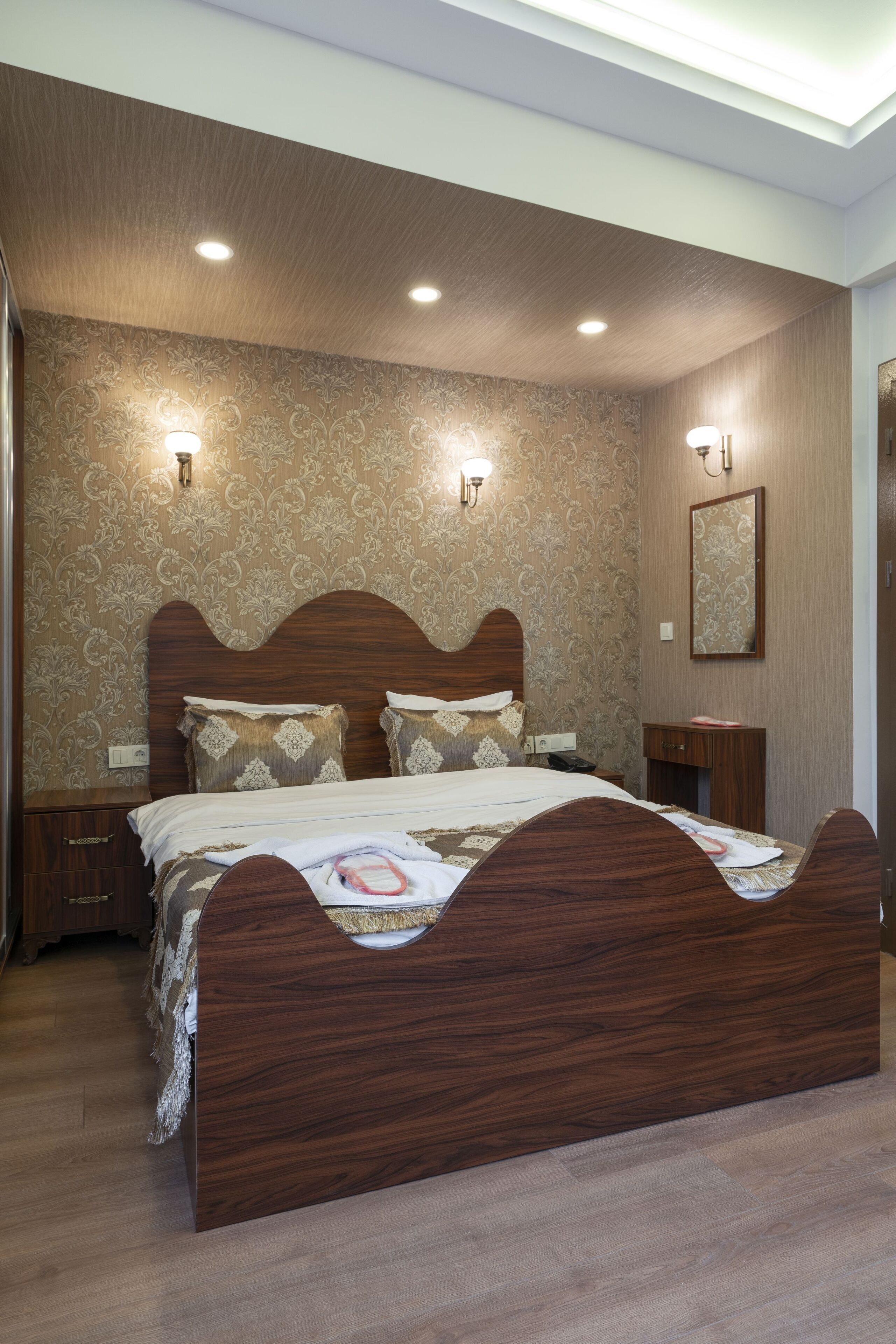 A bedroom with a wooden bed, patterned wallpaper, and two bedside lamps.