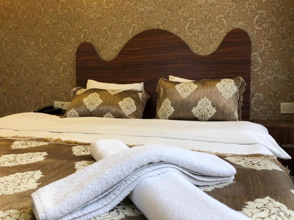 Un lit bien fait, agrémenté d’oreillers à motifs et d’une serviette pliée posée sur une couvre-lit à fleurs.