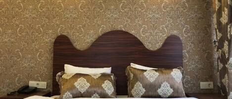 A hotel room with a large bed, two wall-mounted lamps, and a patterned wallpaper.