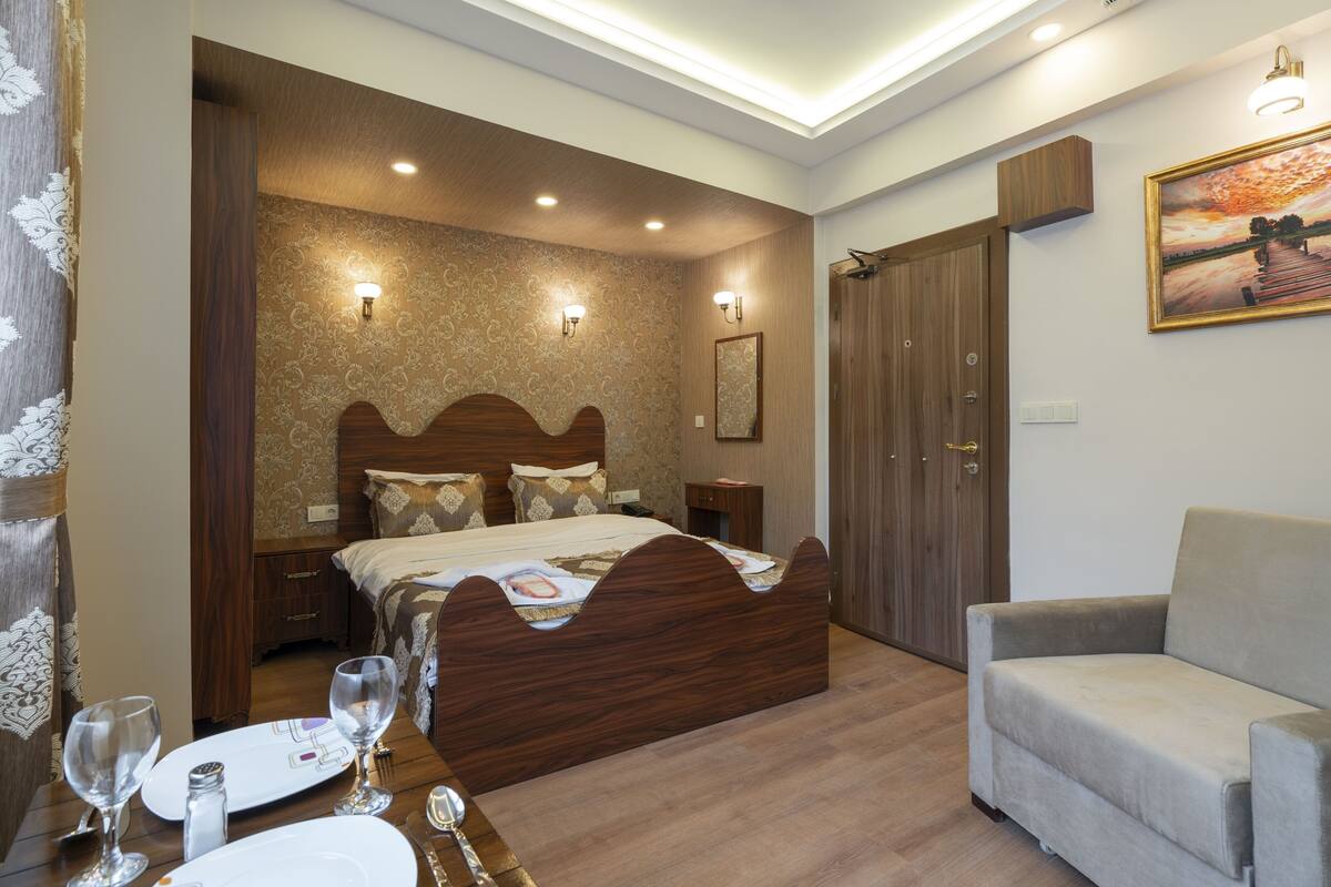 A bedroom with a wooden bed, bedside tables, a chair, and a painting on the wall.