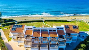Un hotel costero con varios balcones, vista a la playa y paneles solares en el techo.