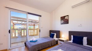 Un dormitorio con dos camas, una puerta corrediza de vidrio a un balcón y un cuadro en la pared.