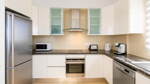 A compact kitchen with a stainless steel refrigerator, a microwave, a toaster, and a coffee maker on the countertop.