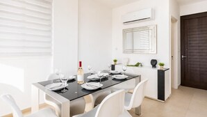 A dining area with a table set for four, a bottle of wine, and a mirror above the table.