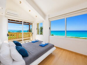 A bedroom with a bed, a view of the ocean, and a balcony with a wooden railing. - Villa Myla - Three Bedroom Villa, Sleeps 5 (Agia Marina Chrysochous)