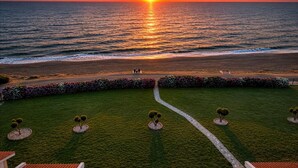 A sunset view over a beach with a pathway leading to a seating area.