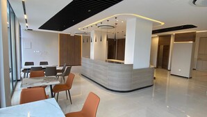 Una moderna hall d'albergo con reception, area lounge e soffitto alto con motivo a griglia nera.