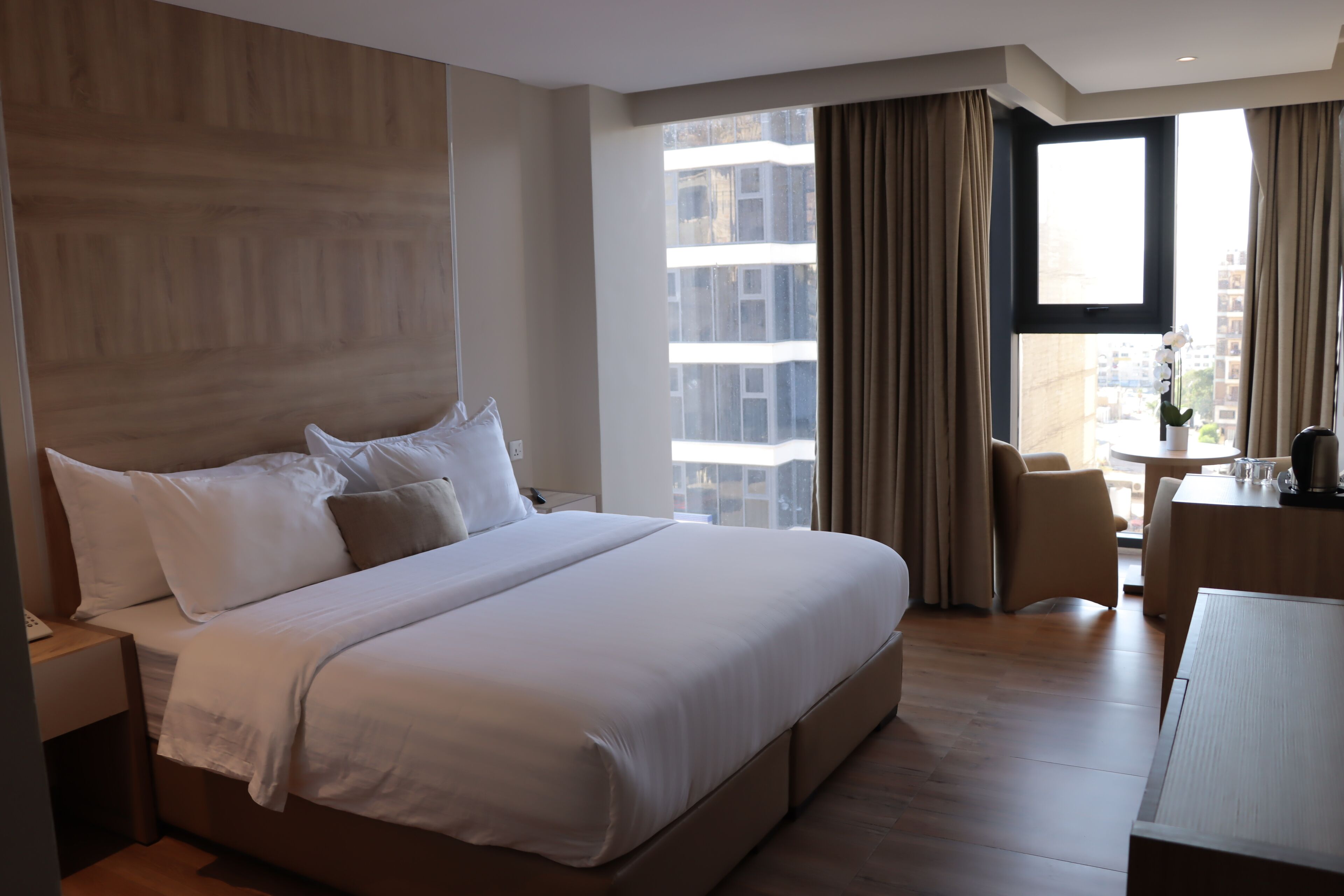 Una habitación de hotel con una cama grande, un escritorio y vistas a la ciudad.
