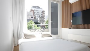 A modern bedroom with a large bed, a TV mounted on the wall, and a balcony with a view of the city. - 801 O "Your Temporary Home (Ciudad Autónoma de Buenos Aires)