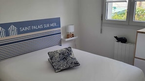 Ein Schlafzimmer mit einem großen Bett, einem Kissen, einem Nachttisch mit Lampe und einem Fenster mit Jalousien.