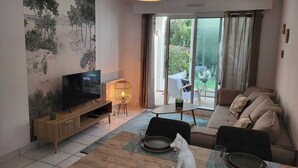 Ein modernes Wohnzimmer mit einem Flachbildfernseher, einem Holztisch, einer Couch und einem Essbereich mit Tisch für zwei Personen.