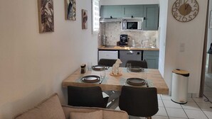 Eine kompakte Küche mit Essbereich, ausgestattet mit Mikrowelle, Kaffeemaschine und Spüle.