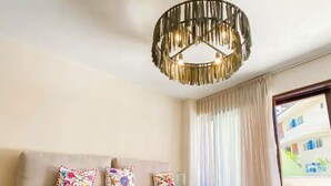 A modern hotel room with a sofa, a wooden coffee table, and a hanging light fixture.